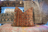 Detailed pattern of rust coral, blue, and green on vintage Persian fragment pillow.