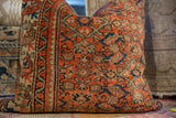 Vintage Persian rug fragment pillow with aged pile, rust coral, and seafoam green motifs.