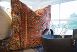 Vintage Persian rug fragment pillow, rust coral geometric pattern, subtle seafoam green linen backing.