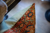 Textured surface of vintage Persian rug fragment pillow, rust coral and seafoam green.