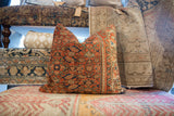 Vintage Persian rug fragment pillow, side view with rust coral, seafoam, ivory geometric border.