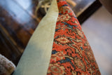 Close-up of vintage Persian rug fragment pillow with rust coral texture, seafoam backing.