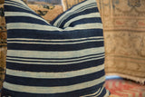 Indigo and light striped vintage African textile pillow with natural weave texture.