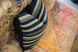 Striped indigo African textile pillow displaying woven texture and navy linen backing.