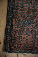Intricate floral blossoms in shades of indigo and sky blue on the dusty copper field of a fine Persian rug.