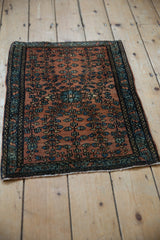 Angled view of a fine Farahan Sarouk rug mat, showing its intricate floral design on a dusty copper field.