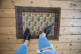 Vintage Persian pictorial mat with human figures, shown overhead for a sense of scale.
