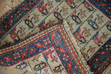 Folded corner of the vintage Persian bagface rug showing the indigo floral border and ivory field.