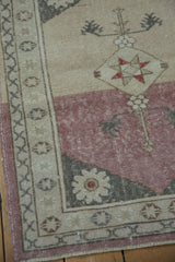 Corner of distressed Anatolian rug featuring dusty raspberry and cream color block.