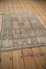 Distressed vintage Melas rug detail: geometric motifs in muted dusty rose and sea foam green.