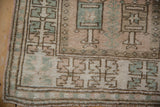 Distressed Melas rug corner with geometric patterns, original side selvage, and muted pile.