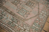 Geometric border of distressed Melas rug, short pile, pastel tones, and visible fringe.
