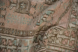 Ruffled pile of the distressed Melas rug, with faded rose and sea foam geometric patterns.