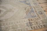Distressed vintage Oushak rug corner featuring faded royal blue, beige geometric patterns, even wear.
