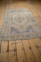 Distressed vintage Oushak rug's secured end with worn pile texture in soft beige and muted blue.