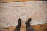 Distressed vintage Oushak runner detail, showing faded pale rose, ivory, and turquoise patterns.