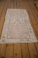 Vintage Distressed Oushak runner with faded pale rose, ivory floral motif and textured wear.