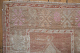 Close-up of the vintage rug's hand-knotted pile, showing the floral border and ivory fringe.