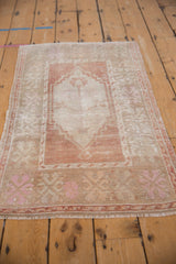 Angled view of a distressed vintage Oushak rug highlighting its soft, faded terracotta and pink tones.