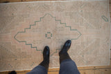 Faded pile of a distressed Oushak runner with dusty rose and pale green stepped medallion.