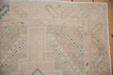 Vintage distressed Oushak runner's evenly worn pile, subtle geometric motifs, and intact side selvage.
