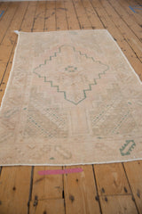 Distressed vintage Oushak runner with stepped emerald green medallion and pale rose geometric motifs.