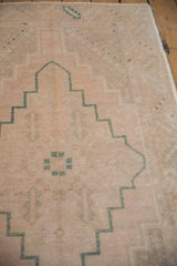 Vintage Distressed Oushak rug's muted dusty rose pile and emerald green stepped geometric design.