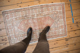 Distressed Turkish Oushak rug with muted mauve, ivory, and silver floral field motifs.