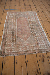Distressed Oushak rug border with pinwheel floral motifs in dusty mauve and antique ivory.