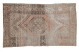 Distressed Oushak rug with hexagonal medallion, finned finials, and muted dusty rose patterns.