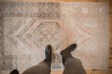Distressed Oushak rug's hexagonal medallion with geometric floral patterns and dusty rose abrash.