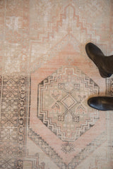 Close-up of distressed vintage Oushak rug with dusty rose and silver geometric medallion, aged texture.