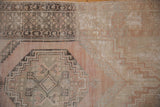 Vintage Oushak rug with prominent distressed pile texture, hexagonal medallion, and geometric motifs.