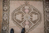 Close-up of vintage Oushak rug showing geometric medallion, varied pile, pink, brown, and cream.