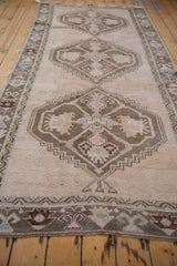Close-up of distressed Oushak rug runner, geometric medallions in cream, chestnut, and pale pink.