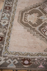 Distressed Oushak runner detail: textured pile, meandering vine border in sage, blue, pink tones.