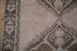 Distressed Oushak runner border detail with geometric patterns in chestnut, pale blue, and ivory.