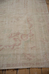Vintage distressed Oushak rug with decorative wear, highlighting ivory and faded raspberry tones.