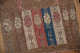 Textured close-up of distressed Oushak rug, featuring columns of dusty raspberry, sapphire blue, and camel.