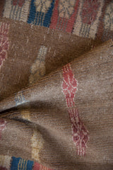 Folded distressed Oushak rug shows worn pile with camel and softened floral patterns.