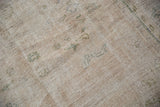 Worn pile texture of vintage distressed Oushak rug, with faint green and ivory patterns.