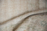 Textured pile of distressed Oushak rug, revealing wear to foundation and subtle ivory and olive tones.