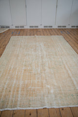 Artfully distressed vintage Oushak rug with worn pile exposing foundation in cream and sea foam green.