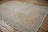 Vintage distressed Oushak carpet showing worn pile, exposed foundation, and mint green motifs.
