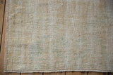 Distressed Oushak rug texture with visible foundation and soft cream, olive hues.