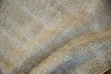Distressed Oushak rug's textured pile and visible foundation in cream, gold, and olive.