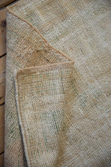 Textured and distressed cream Oushak rug pile with subtle green hues and intact side selvage.