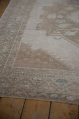 Distressed Oushak runner showing worn beige pile, geometric border, and intact side selvage.