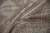 Distressed Oushak rug texture with even wear, soft beige tones, and subtle geometric patterns.