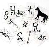 A collection of vintage style lightbox tiles with black letters, numbers, and wilderness symbols.